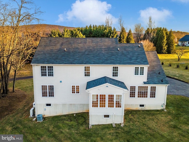 back of house with central AC and a lawn