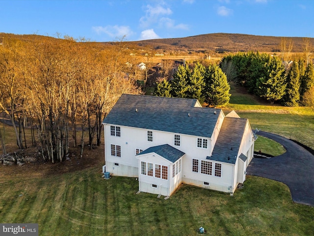 back of property with a sunroom, a yard, and a mountain view