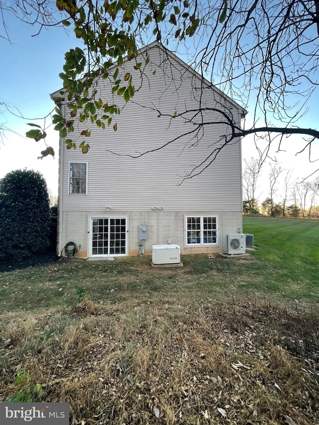 rear view of house with ac unit and a yard