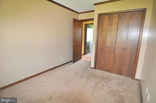 unfurnished bedroom with ornamental molding, light colored carpet, and a closet