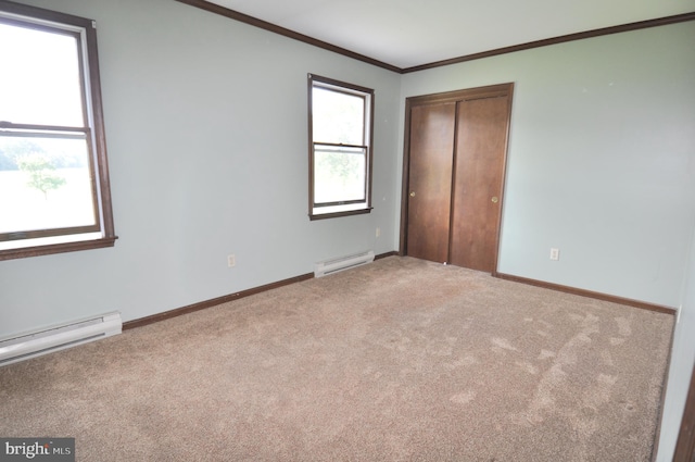 unfurnished bedroom featuring a closet, baseboard heating, carpet flooring, and crown molding