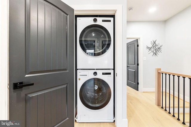 laundry room with light hardwood / wood-style flooring and stacked washer / drying machine