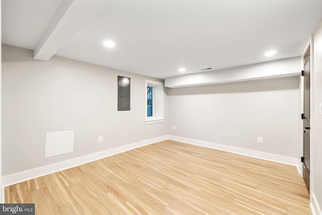 basement with electric panel and light hardwood / wood-style floors