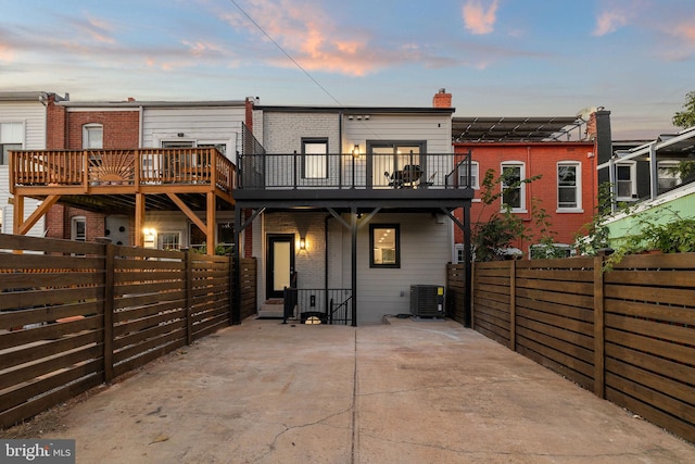 back house at dusk with a patio and central AC unit