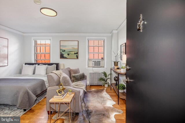 bedroom with light wood-type flooring, cooling unit, radiator, and ornamental molding