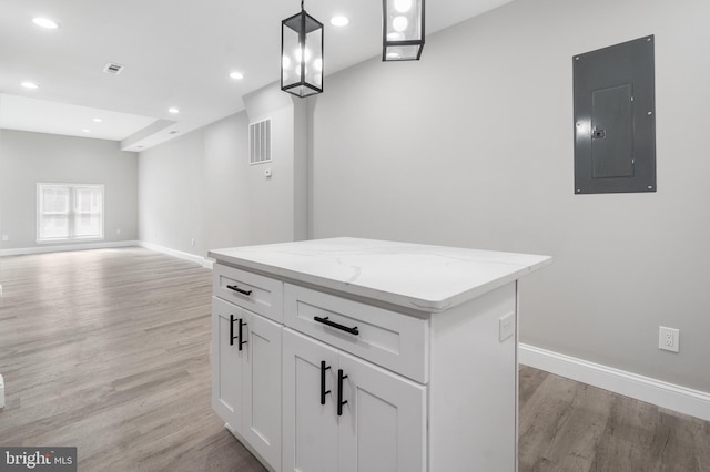 kitchen with white cabinets, pendant lighting, a center island, light hardwood / wood-style flooring, and electric panel