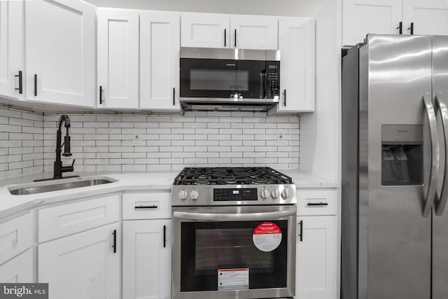 kitchen featuring sink, white cabinets, backsplash, appliances with stainless steel finishes, and light stone countertops