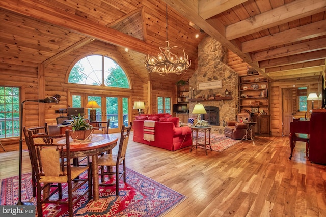 dining space featuring a fireplace, beam ceiling, light hardwood / wood-style flooring, and wood ceiling