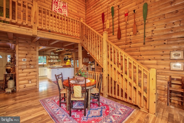 dining area with log walls, a high ceiling, and light wood-type flooring