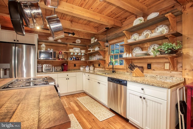 kitchen featuring pendant lighting, stainless steel appliances, white cabinetry, and light hardwood / wood-style floors