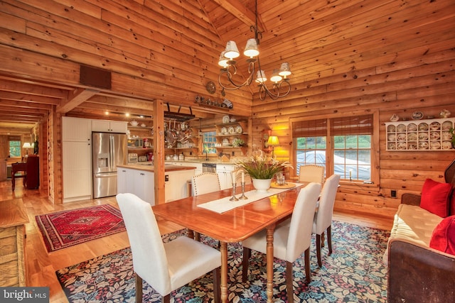 dining room with beamed ceiling, high vaulted ceiling, light hardwood / wood-style flooring, and rustic walls