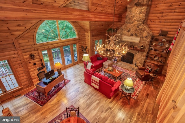 living room with light wood-type flooring, high vaulted ceiling, a stone fireplace, and wooden ceiling