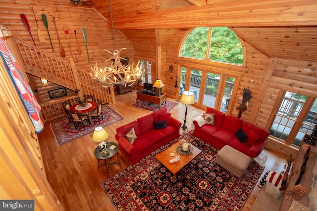 living room with beam ceiling, high vaulted ceiling, wooden ceiling, a chandelier, and light hardwood / wood-style floors