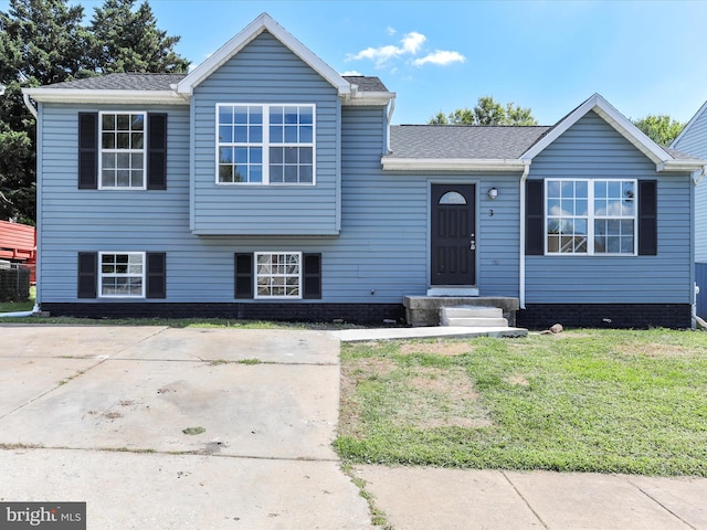 tri-level home featuring a shingled roof and a front lawn