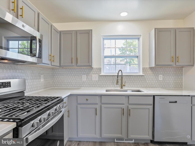 kitchen with a wealth of natural light, sink, appliances with stainless steel finishes, and light hardwood / wood-style floors