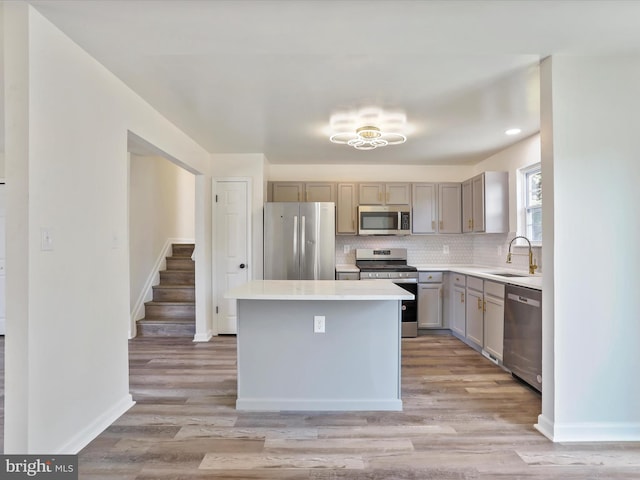 kitchen with light wood-type flooring, tasteful backsplash, stainless steel appliances, a center island, and sink