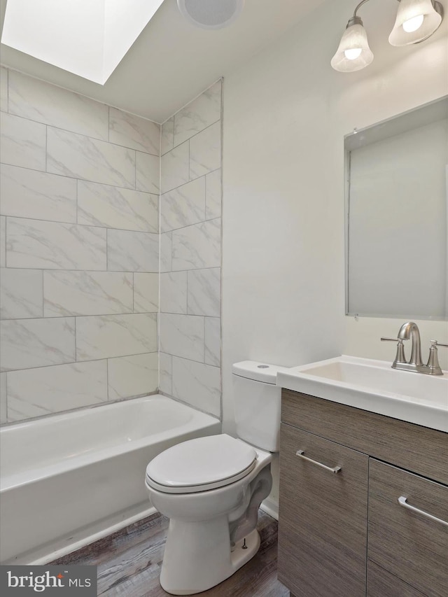 full bathroom with hardwood / wood-style floors, tiled shower / bath, toilet, and vanity