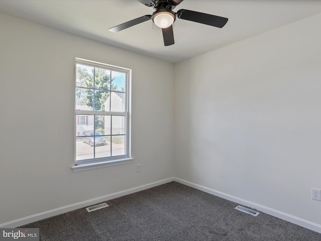 spare room featuring dark colored carpet, visible vents, and baseboards