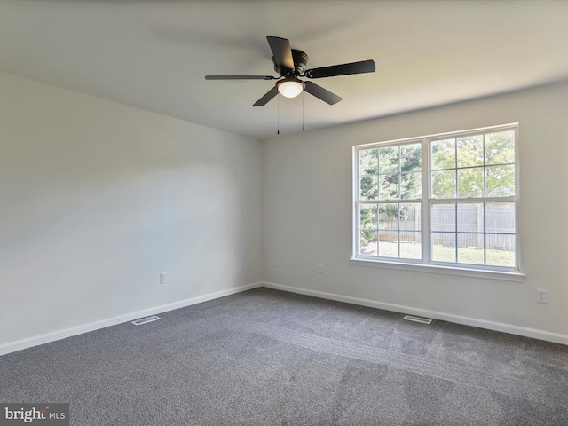 empty room with a ceiling fan, baseboards, visible vents, and dark carpet