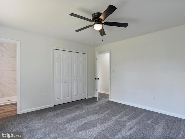 unfurnished bedroom featuring baseboards, ceiling fan, dark carpet, a closet, and ensuite bath