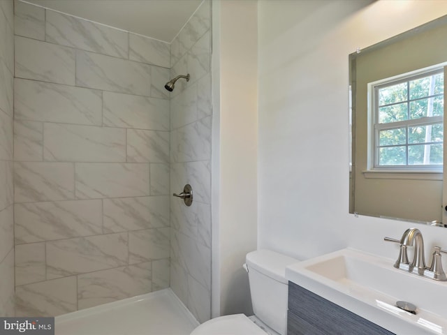 bathroom featuring tiled shower, vanity, and toilet