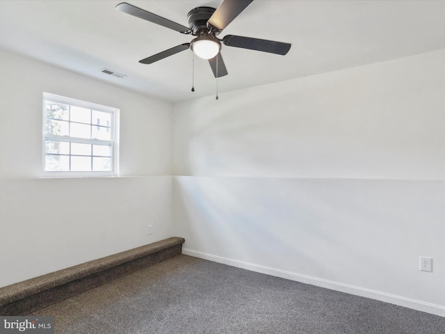 carpeted empty room with baseboards, visible vents, and ceiling fan