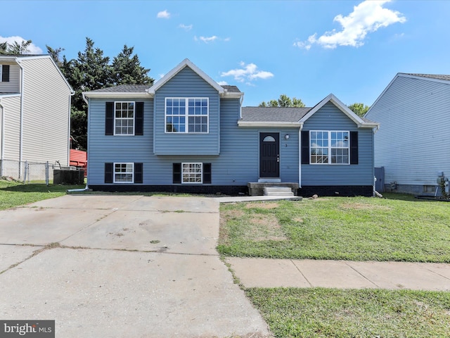 split level home featuring a front yard, central AC unit, and fence