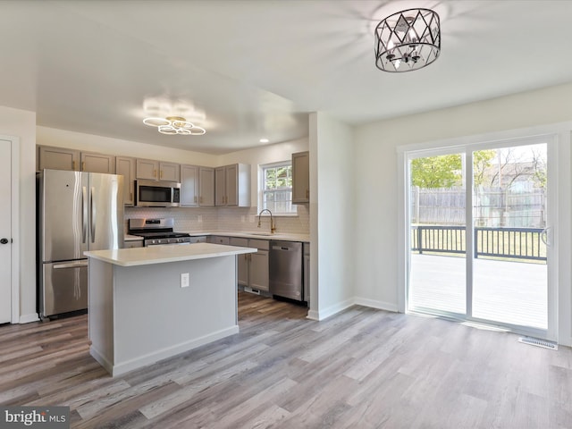 kitchen with a wealth of natural light, light hardwood / wood-style flooring, stainless steel appliances, and sink