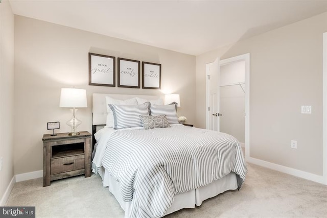 bedroom featuring a walk in closet, light colored carpet, and a closet