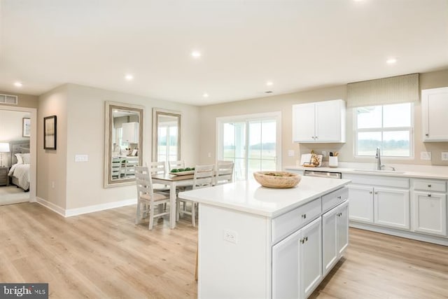 kitchen featuring a center island, white cabinetry, sink, and light hardwood / wood-style floors