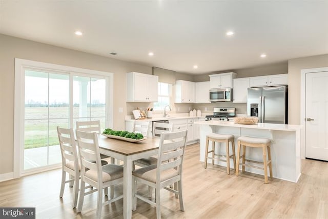 dining space with a wealth of natural light, light hardwood / wood-style floors, and sink