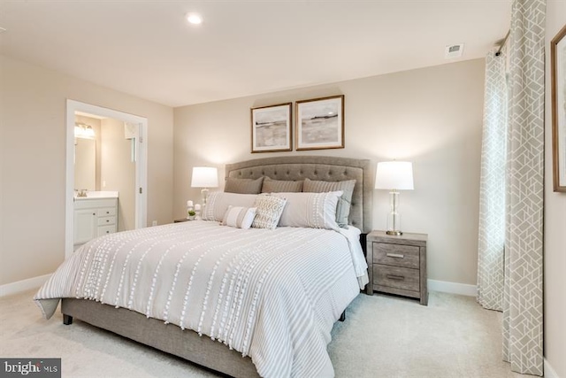 bedroom featuring ensuite bath and light carpet