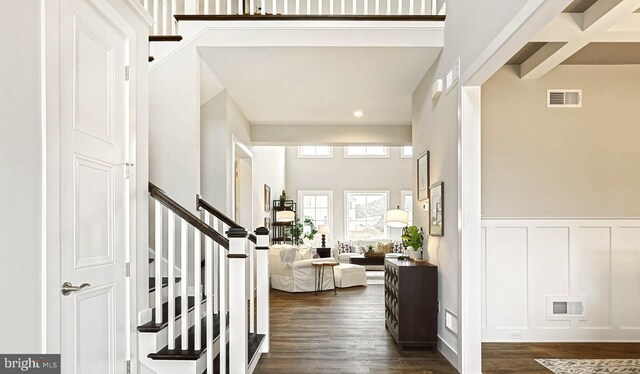 entryway featuring a high ceiling, beam ceiling, and dark wood-type flooring