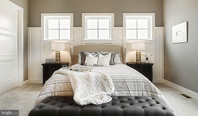 bedroom featuring light carpet and multiple windows