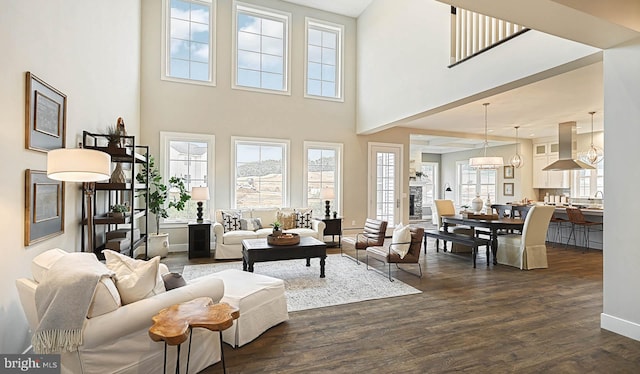 living room featuring a towering ceiling, a chandelier, and dark hardwood / wood-style flooring