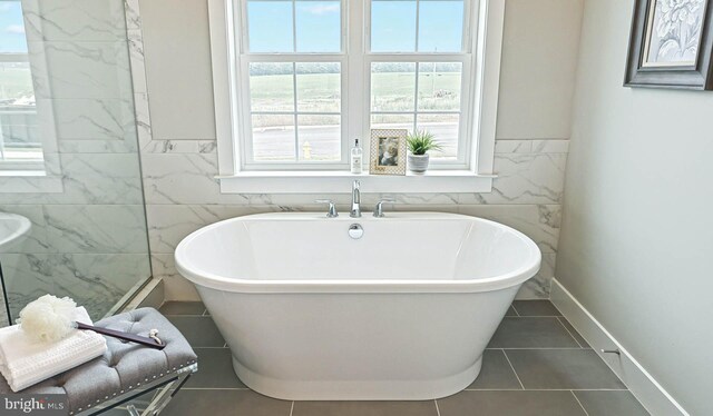 bathroom featuring tile walls, tile patterned flooring, and a bath