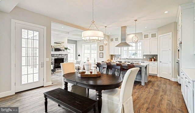 dining area with a stone fireplace, sink, and hardwood / wood-style floors