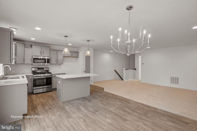 kitchen featuring sink, decorative light fixtures, gray cabinets, appliances with stainless steel finishes, and light hardwood / wood-style floors