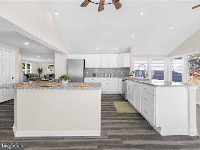 kitchen with white cabinetry, sink, appliances with stainless steel finishes, a center island, and dark wood-type flooring