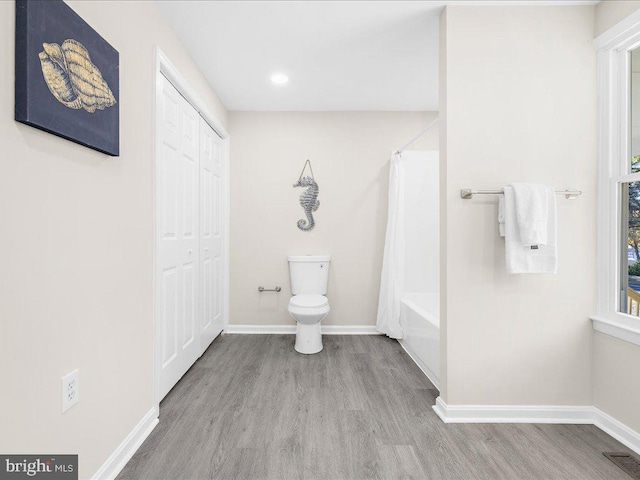 bathroom with shower / bath combo with shower curtain, hardwood / wood-style flooring, and toilet