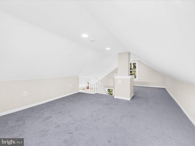 additional living space featuring dark colored carpet and lofted ceiling