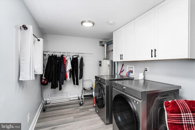 clothes washing area featuring washing machine and dryer, light hardwood / wood-style flooring, gas water heater, and cabinets