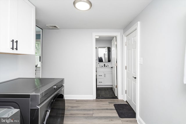 laundry room featuring light hardwood / wood-style flooring, independent washer and dryer, cabinets, and sink