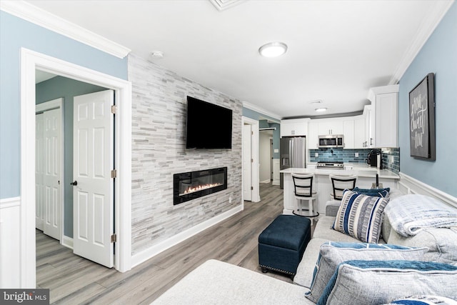 living room featuring light hardwood / wood-style flooring, a fireplace, and crown molding