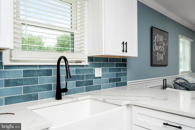 details with ornamental molding, white cabinets, light stone counters, and sink