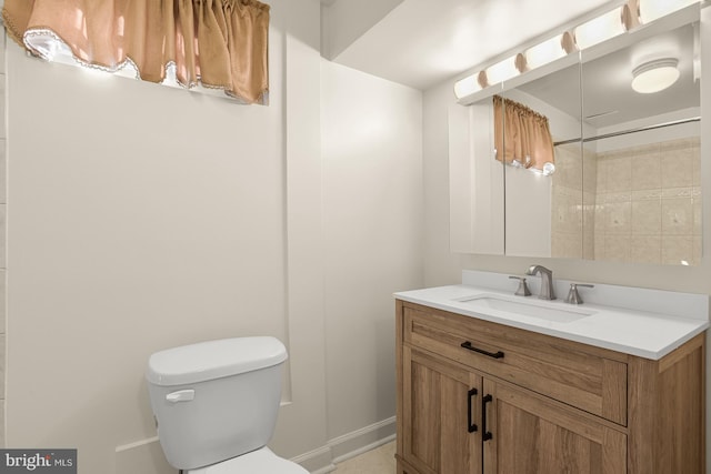 bathroom with tiled shower, vanity, and toilet