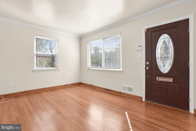 entryway with a wealth of natural light, light wood-type flooring, and crown molding