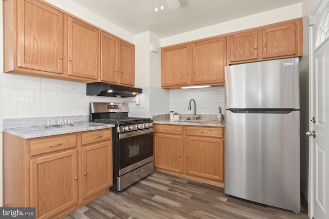 kitchen featuring light stone counters, sink, tasteful backsplash, dark wood-type flooring, and appliances with stainless steel finishes