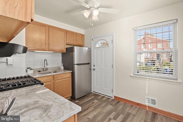 kitchen featuring dark hardwood / wood-style floors, sink, ventilation hood, stainless steel refrigerator, and decorative backsplash