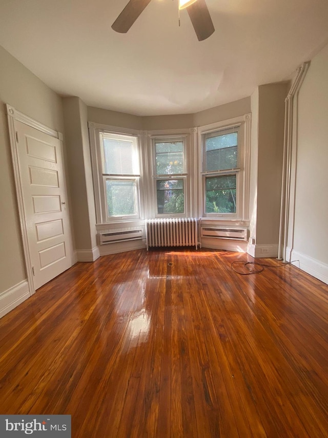 interior space with dark wood-type flooring, ceiling fan, a wealth of natural light, and radiator heating unit